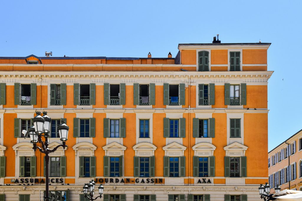 A vibrant orange building in Nice, showcasing classic French architecture under a clear blue sky.