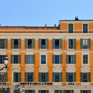 A vibrant orange building in Nice, showcasing classic French architecture under a clear blue sky.